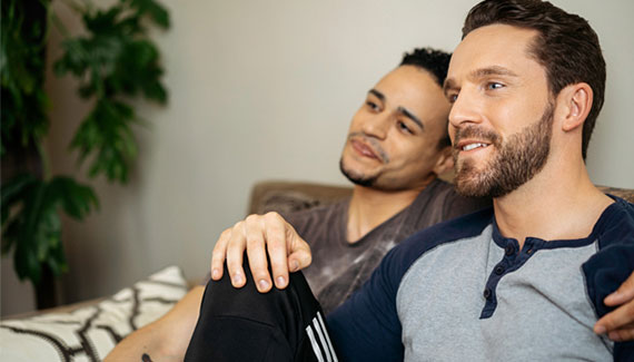 Two men sitting on a couch watching tv together