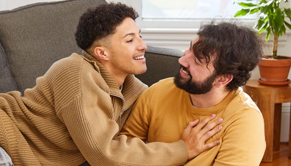 Two men in their living room in loving embrace