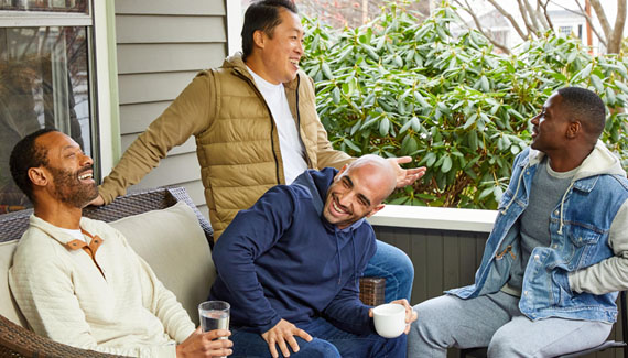 Group of men sitting on outdoor porch laughing and talking