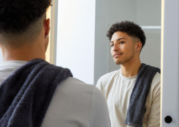 Bi-racial young man looking at reflection in mirror in bathroom