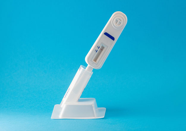 An at home HIV test, displayed at an angle against a bright blue background.